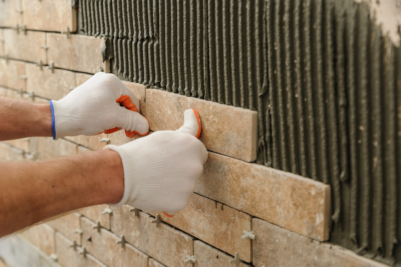 Installing the tiles on the wall. Installing the tiles on the wall. A worker putting tiles in the form of brick.