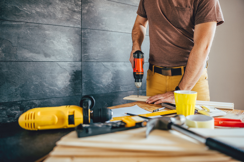 Man drilling wood with battery power Drill Man drilling wood with battery power Drill on the table at home